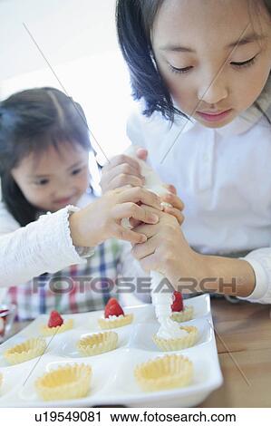 Stock Image - Sisters Making Cakes. Fotosearch