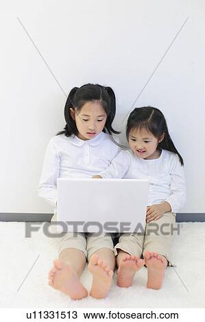Stock Image - Sisters Using Laptop. Fotosearch