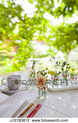 Stock Image - Tea Cup, Book and Rose on Garden Table. Fotosearch