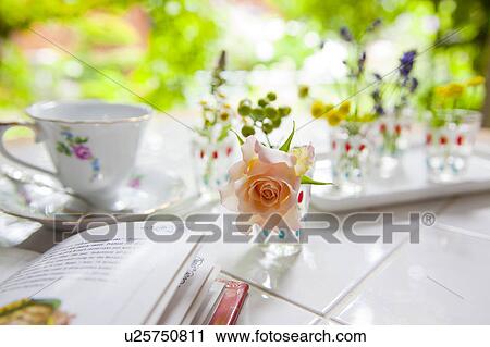 Stock Image - Tea Cup, Book and Rose on Garden Table. Fotosearch