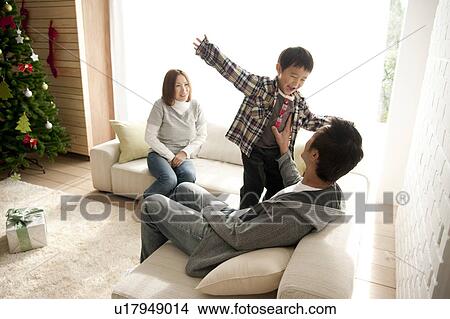 Picture - Two Parents and Son in Living Room at Christmas. Fotosearch