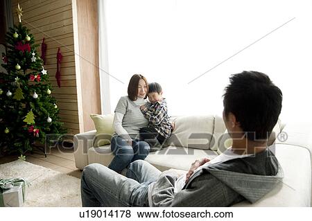 Stock Photo - Two Parents and Son in Living Room at Christmas. Fotosearch