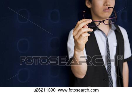 Stock Image - Young man holding his glasses. Fotosearch