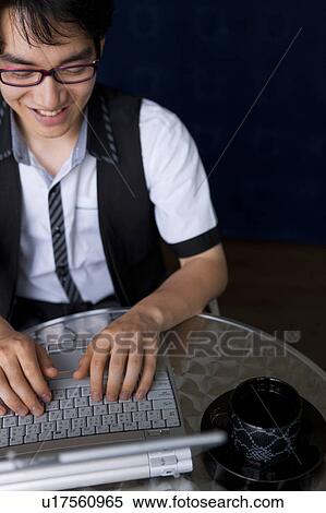 Stock Photography - Young man using laptop at cafe. Fotosearch