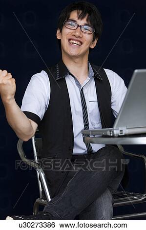 Stock Photograph - Young man with laptop making a fist. Fotosearch