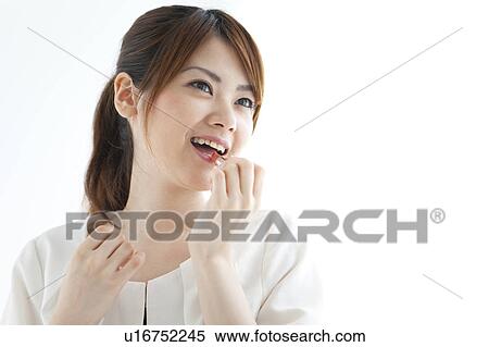 Stock Photography - Young woman applying lipstick. Fotosearch
