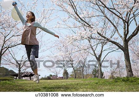Stock Photo - Young woman jumping with balloon. Fotosearch