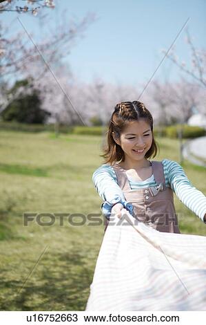 Stock Image - Young woman laying picnic blanket. Fotosearch