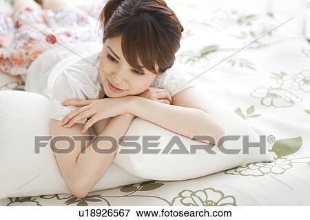 Stock Photo - Young woman lying on bed. Fotosearch