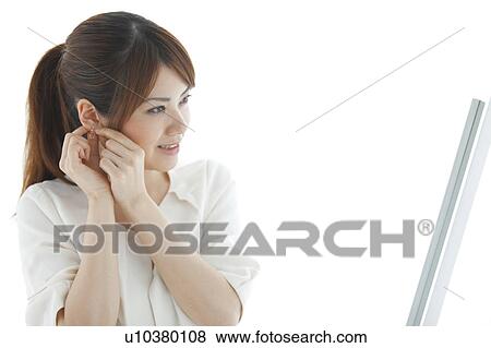 Young woman putting on earring View Large Photo Image Stock Photo - Young woman putting on earring. Fotosearch