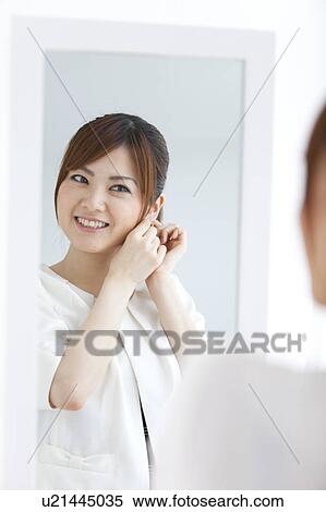 Stock Photography - Young woman putting on earring. Fotosearch