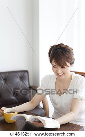 Stock Image - Young woman reading a book. Fotosearch