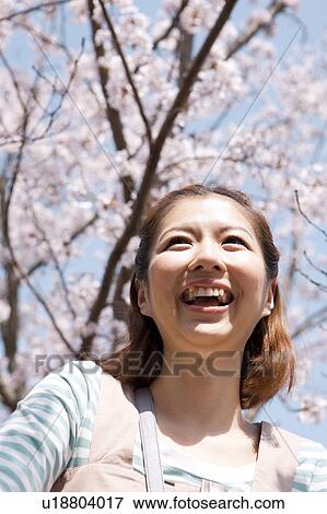 Stock Photo - Young woman smiling, low angle view. Fotosearch