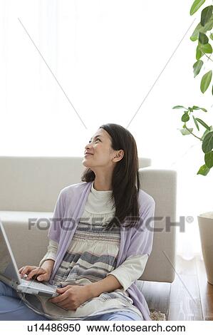 Stock Image - Young woman using laptop. Fotosearch