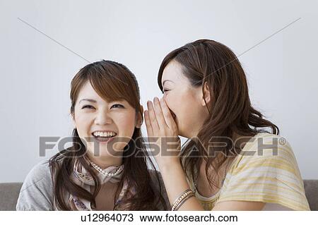 Young woman whispering to another young woman View Large Photo Image Stock Image - Young woman whispering to another young woman. Fotosearch