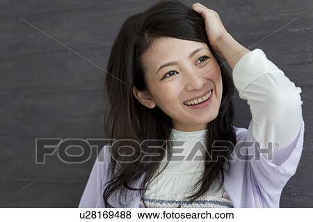 Stock Photo - Young woman with hand in hair. Fotosearch