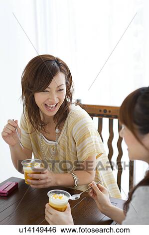 Young women at a cafe talking View Large Photo Image Stock Photograph - Young women at a cafe talking. Fotosearch