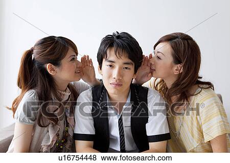 Stock Photo - Young women whispering to young man. Fotosearch