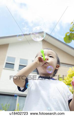 Stock Image - Baby Boy Blowing Bubbles, Low Angle View. Fotosearch