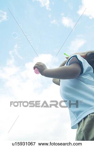 Stock Photo - Baby Boy Blowing Bubbles, Low Angle View. Fotosearch