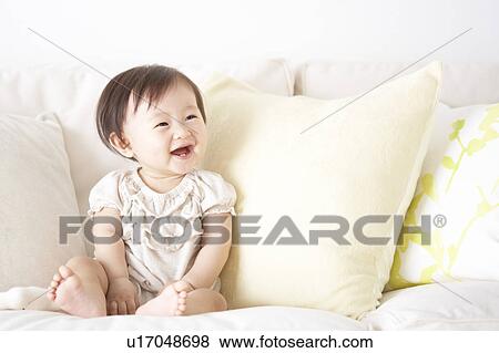 Baby sitting on sofa smiling View Large Photo Image Stock Photo - Baby sitting on sofa smiling. Fotosearch