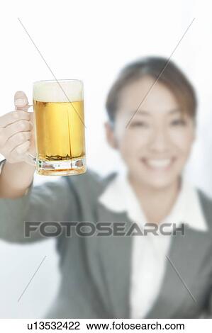 Stock Image - Businesswoman holding a glass of beer, Tokyo Prefecture, Japan. Fotosearch