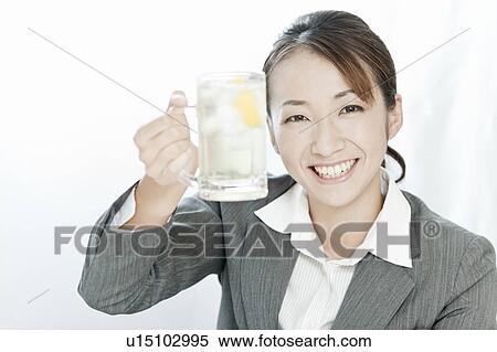 Stock Photography - Businesswoman holding a glass of highball, Tokyo Prefecture, Japan. Fotosearch