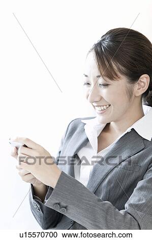 Stock Image - Businesswoman using a smart phone, Tokyo Prefecture, Japan. Fotosearch