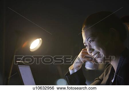 Businesswoman using laptop and holding a can of beer in the dark, Tokyo Prefecture, Honshu, Japan View Large Photo Image Stock Photograph - Businesswoman using laptop and holding a can of beer in the dark, Tokyo Prefecture, Honshu, Japan. Fotosearch