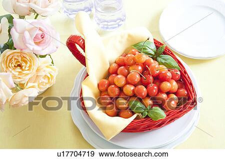 Stock Photo - Cherries in a basket and roses in a vase on table. Fotosearch