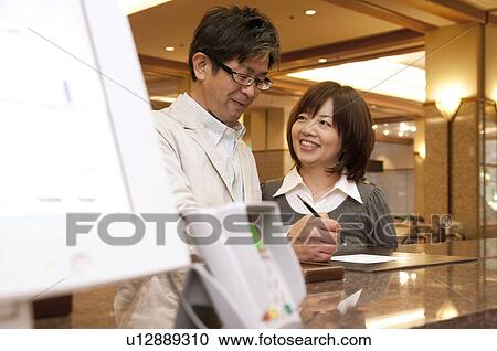 Stock Image - Couple Checking In Hotel. Fotosearch