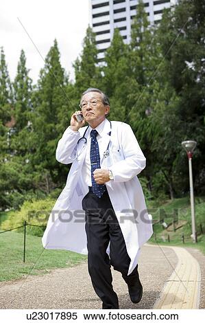 Stock Photography - Doctor Running Whilst On The Phone. Fotosearch