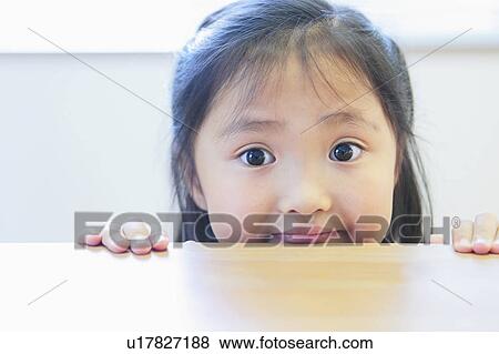 Stock Photo - Girl Peering Behind Table. Fotosearch