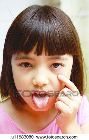 Stock Image - Girl Sticking Out Tongue and Pointing To Her Eye. Fotosearch