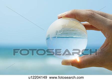 Hand Holding Glass Globe, Sea in Background View Large Photo Image Stock Photo - Hand Holding Glass Globe, Sea in Background. Fotosearch