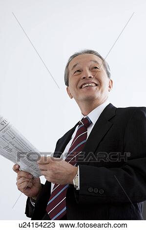 Stock Image - Mature Businessman with Newspaper, Low Angle View. Fotosearch
