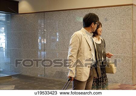 Stock Image - Mature Couple Arriving in Hotel. Fotosearch