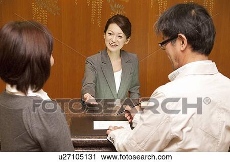 Stock Image - Mature Couple at Hotel Reception. Fotosearch