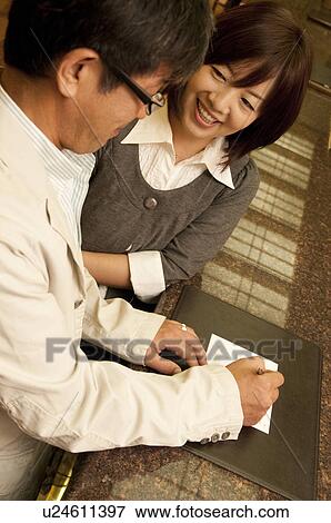 Stock Photo - Mature Couple Checking In To Hotel, High Angle View. Fotosearch