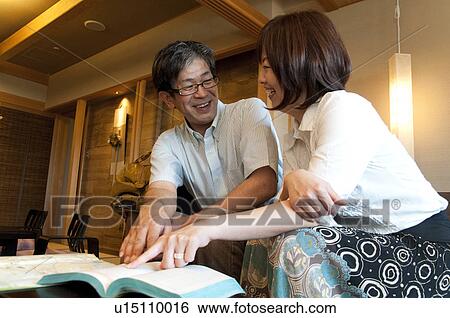 Stock Photograph - Mature Couple Pointing at Guidebook. Fotosearch