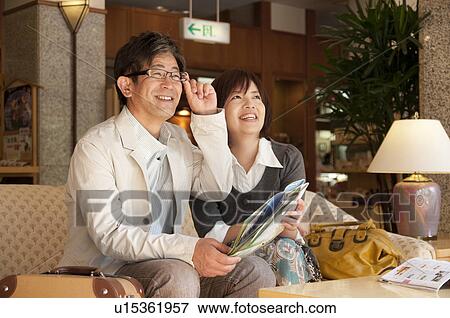 Stock Photo - Mature Couple Sitting in Hotel Lobby and Planning Trip. Fotosearch