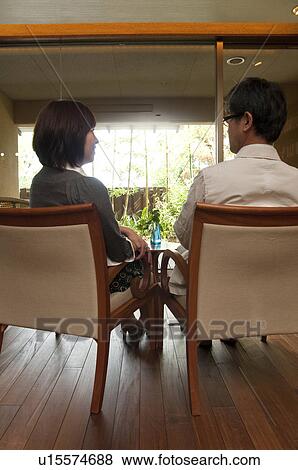 Stock Photo - Mature Couple Sitting on Chairs and Looking at Each Other. Fotosearch