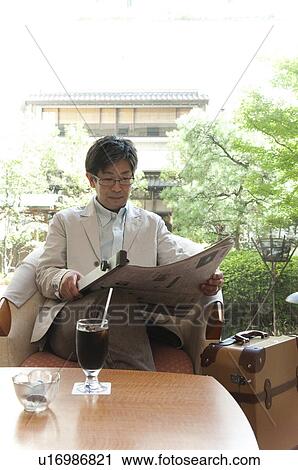Stock Image - Mature Man Reading Newspaper in Lobby. Fotosearch