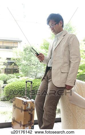 Stock Image - Mature Man Using Mobile Phone in Lobby. Fotosearch