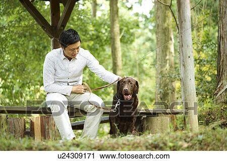 Stock Image - Mid Adult Man Sitting on Bench with His Labrador Retriever. Fotosearch
