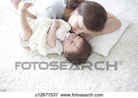 Stock Photo - Mother and baby lying on the floor. Fotosearch