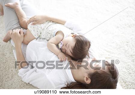 Mother lying on the floor and embracing baby View Large Photo Image Stock Image - Mother lying on the floor and embracing baby. Fotosearch