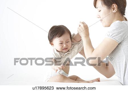 Stock Image - Mother undressing baby. Fotosearch