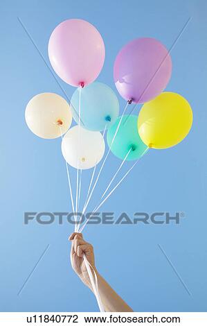 Stock Image - Person Holding Up Balloons. Fotosearch