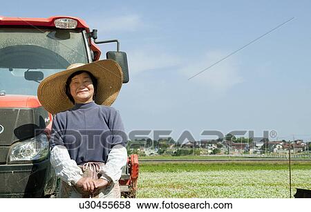 Stock Photo - Senior Woman Standing Next To Tractor. Fotosearch